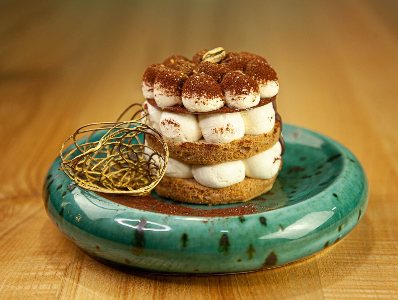 A layered tiramisu on a verdigris ceramic plate